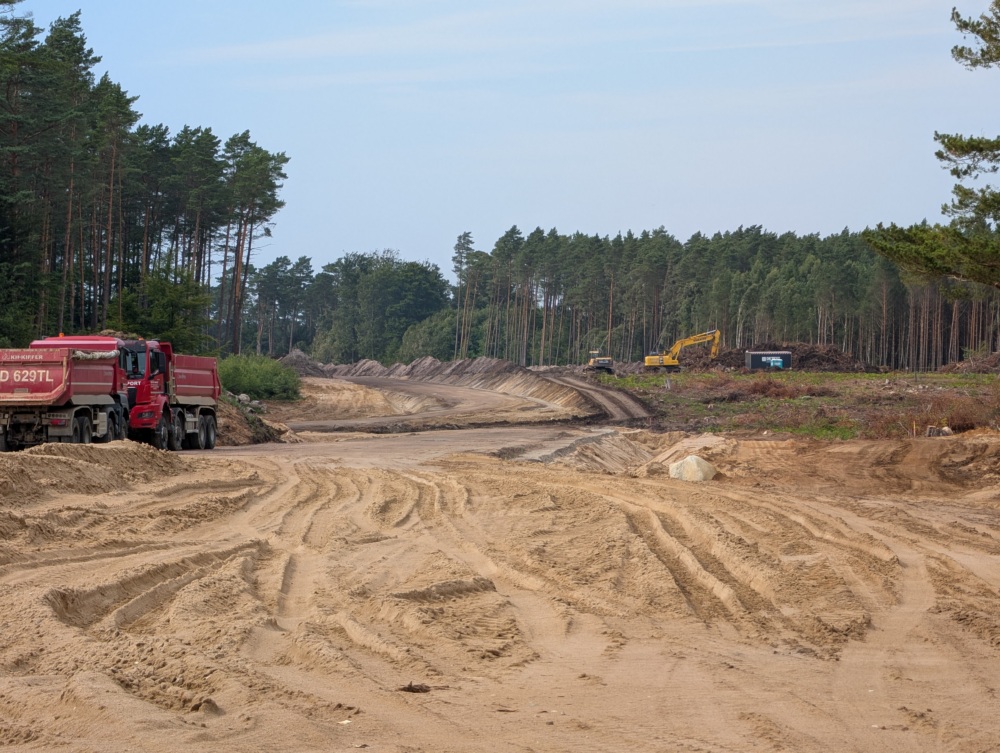 Cleared forest and heavy machinery, surrounded by remaining trees.
