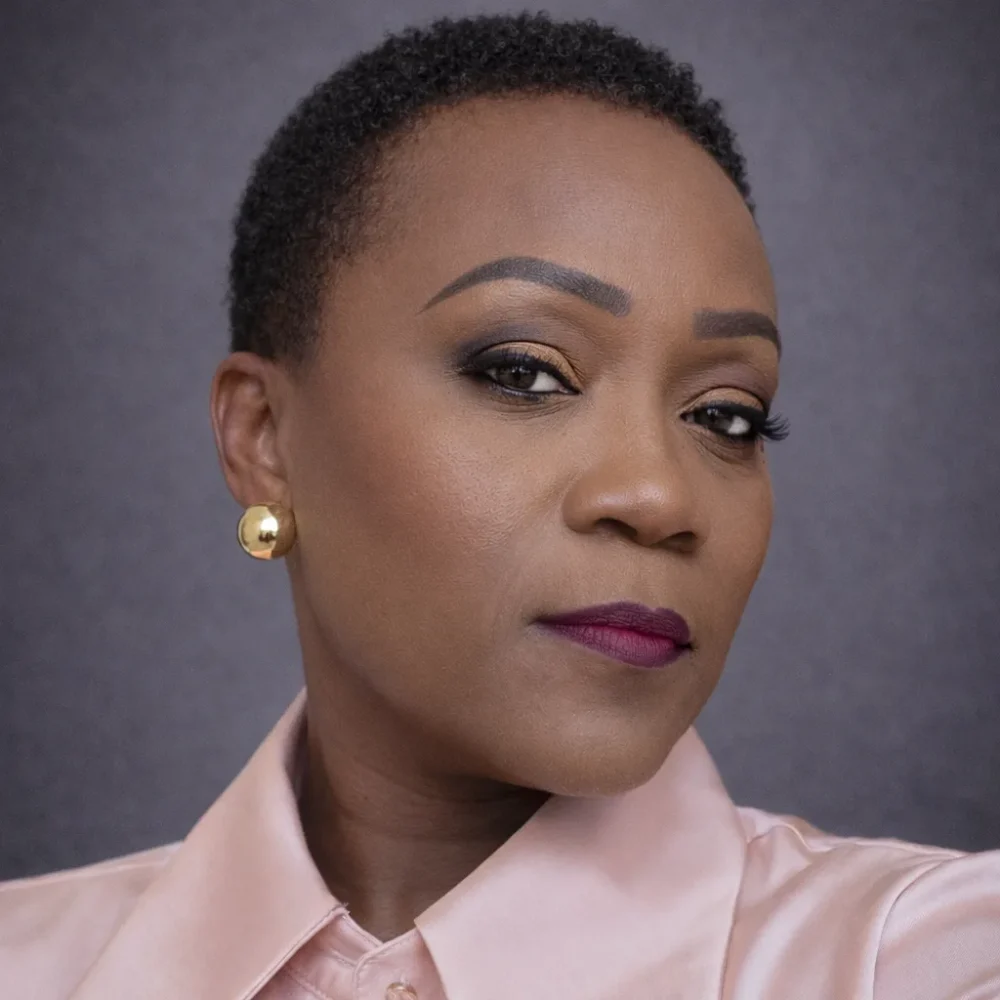 headshot of a woman in a pink shirt with a serious expression.