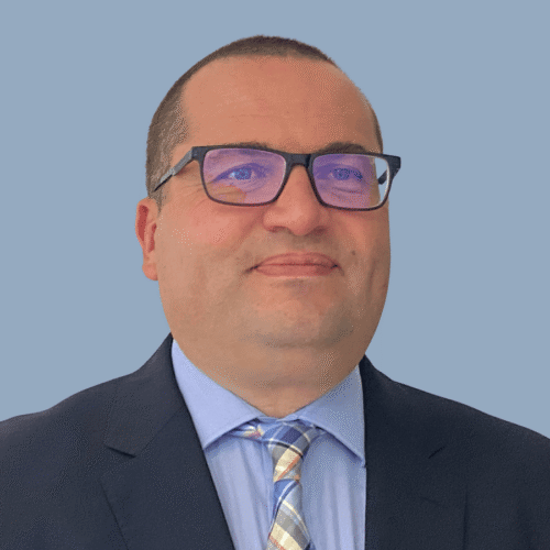 Headshot of a man in glasses wearing a suit.